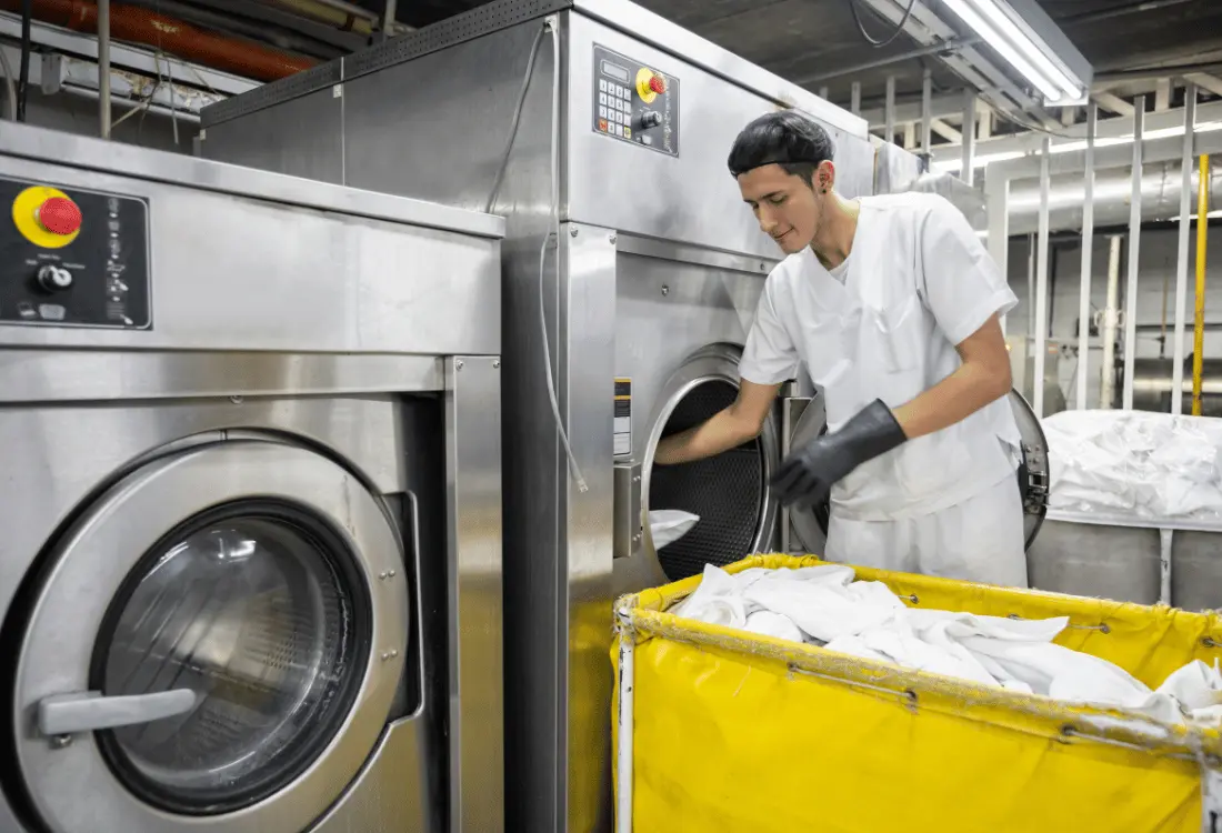A man working in an industrial laundry service, using water soluble laundry bag for infection control.