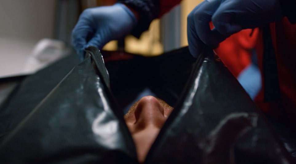 A paramedic dealing with someone in a body bag in the hospital after an unanticipated event